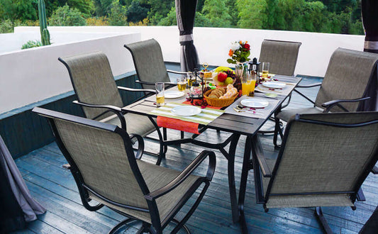 Outdoor dining setup with MEOOEM swivel chairs, table setting, fruit, and drinks in a garden terrace.