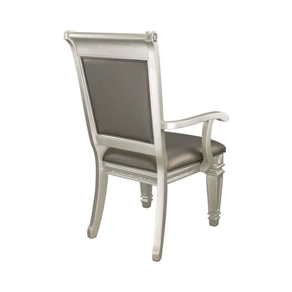 Elegant silver chair with cushioned seat and backrest, featuring detailed woodwork on the legs and armrests.