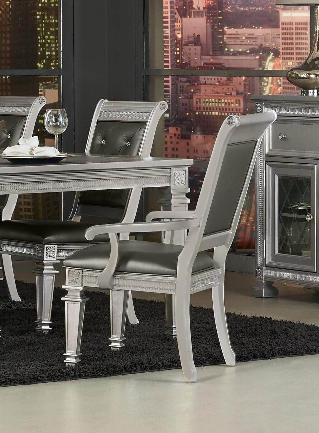 Silver finish dining set with crystal-tufted chairs and table, featuring 2 armchairs and a cityscape background for a modern glam look.