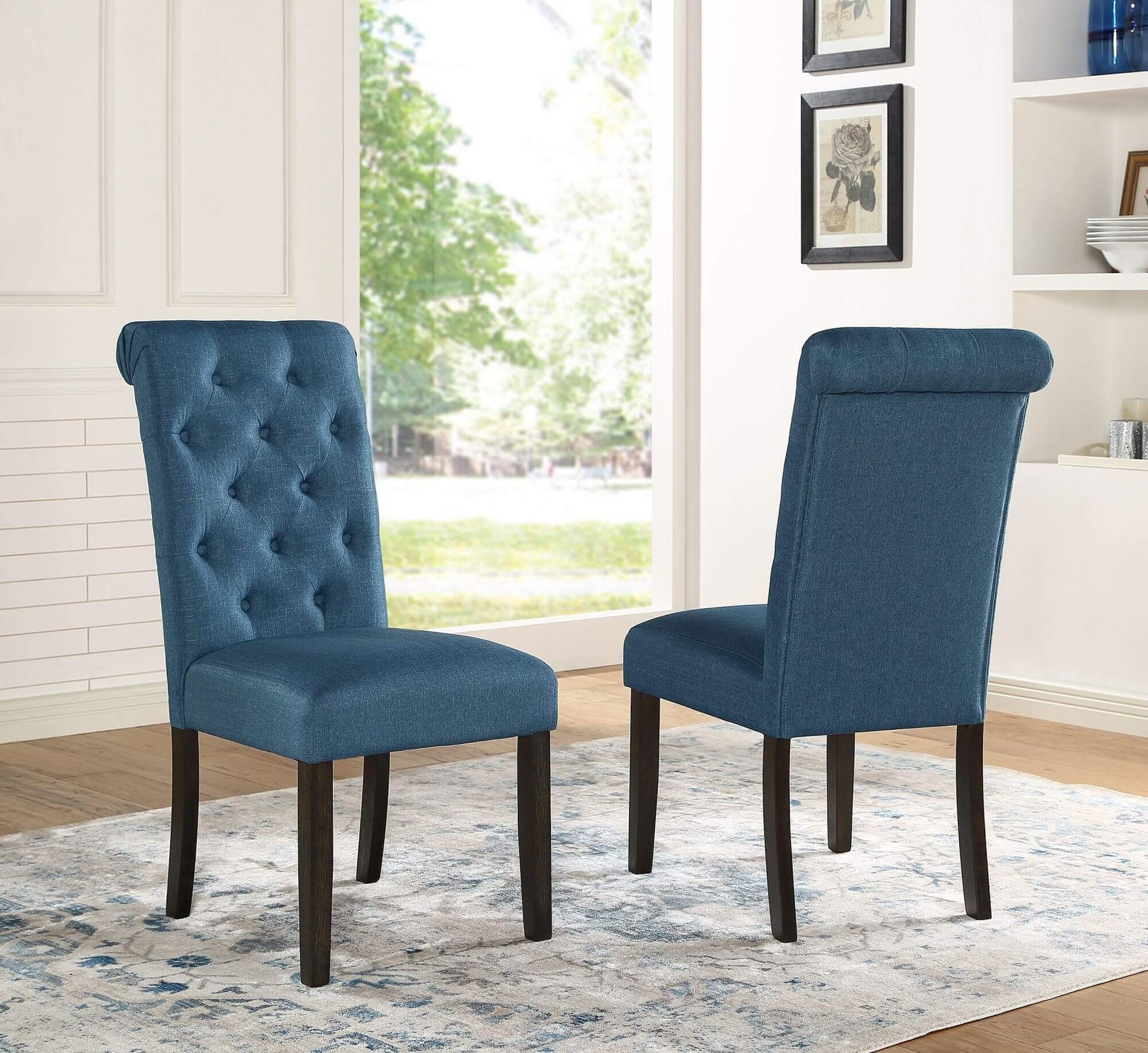 Two elegant blue upholstered dining chairs with tufted backrests, placed in a bright, stylish room.