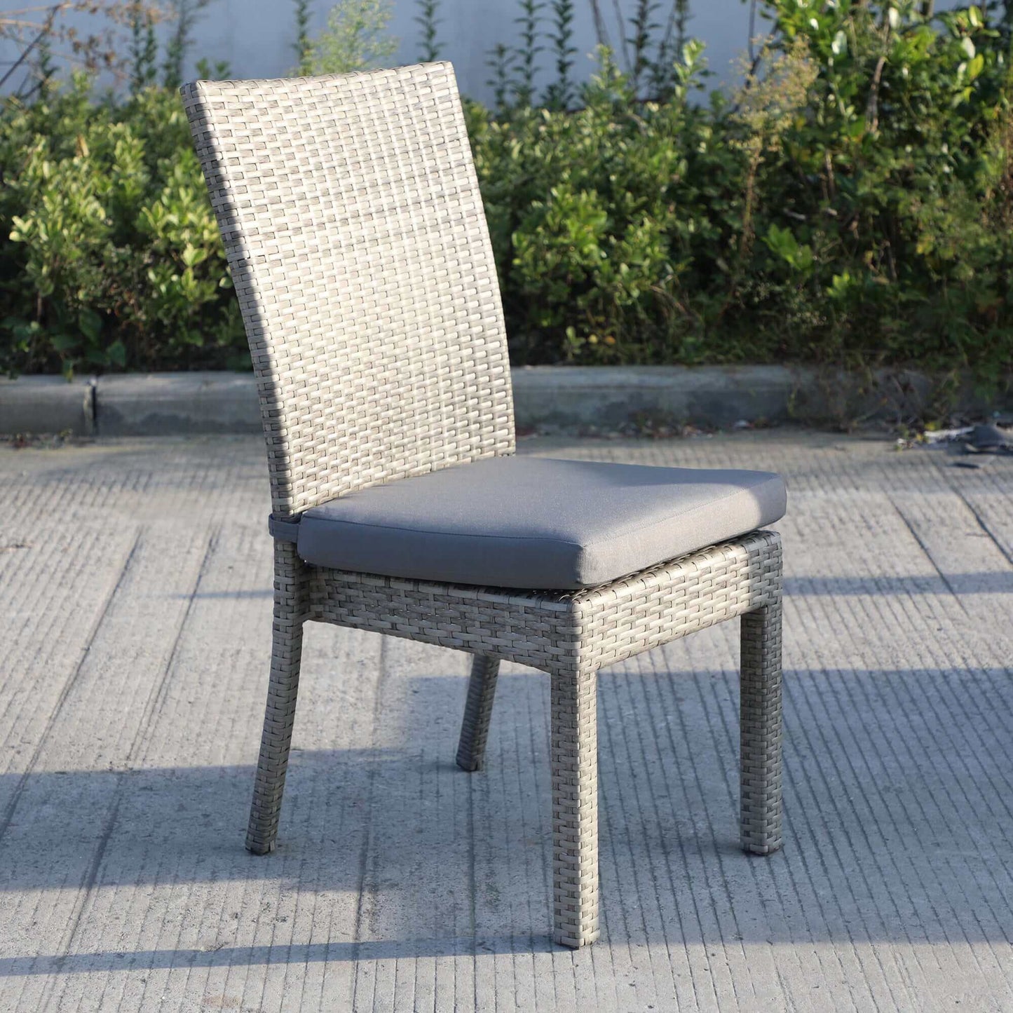 Single chair from Balcones 9-Piece Outdoor Dining Table Set in gray wicker with dark gray cushion, set against outdoor foliage.