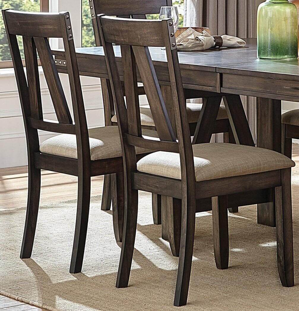 Rustic industrial style dining chairs with beige cushions and wooden table in dining room setting with natural light.