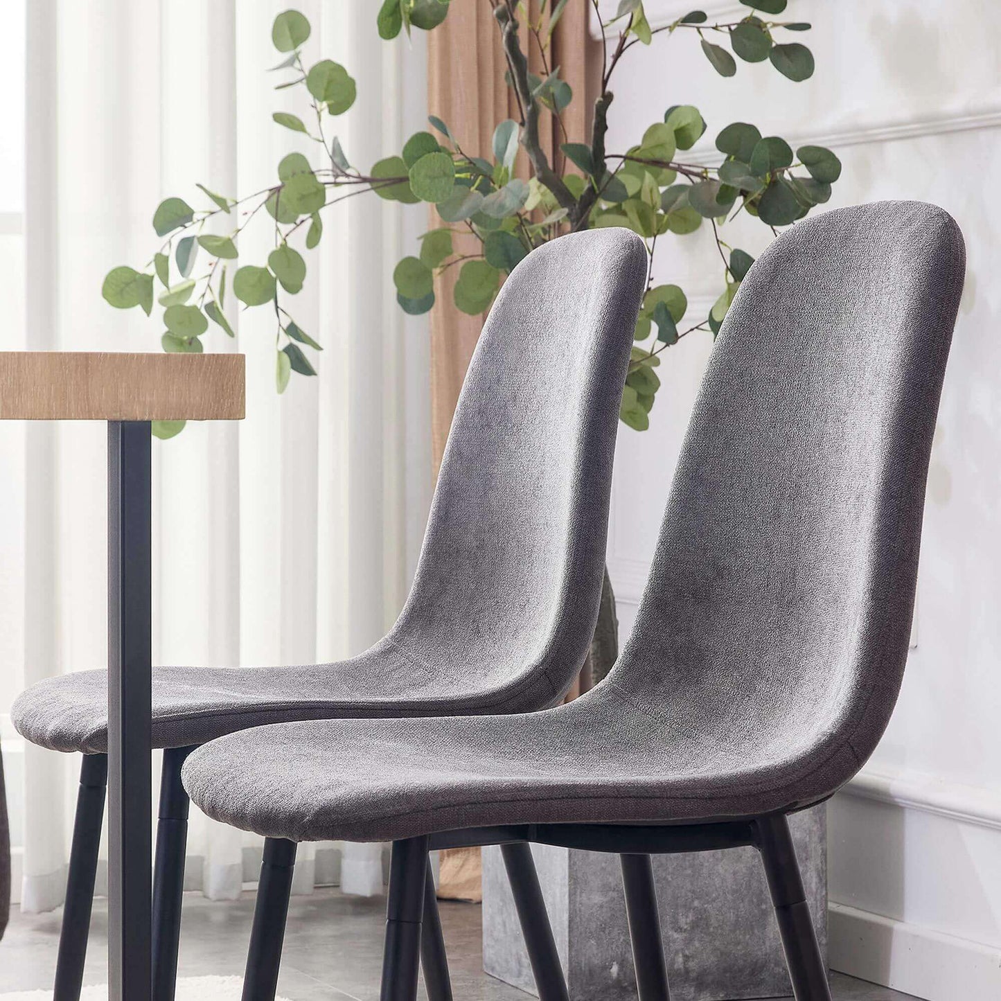 Set of 2 modern medieval style chairs in dark gray, placed by a table, ideal for kitchen, lounge, or breakroom seating.