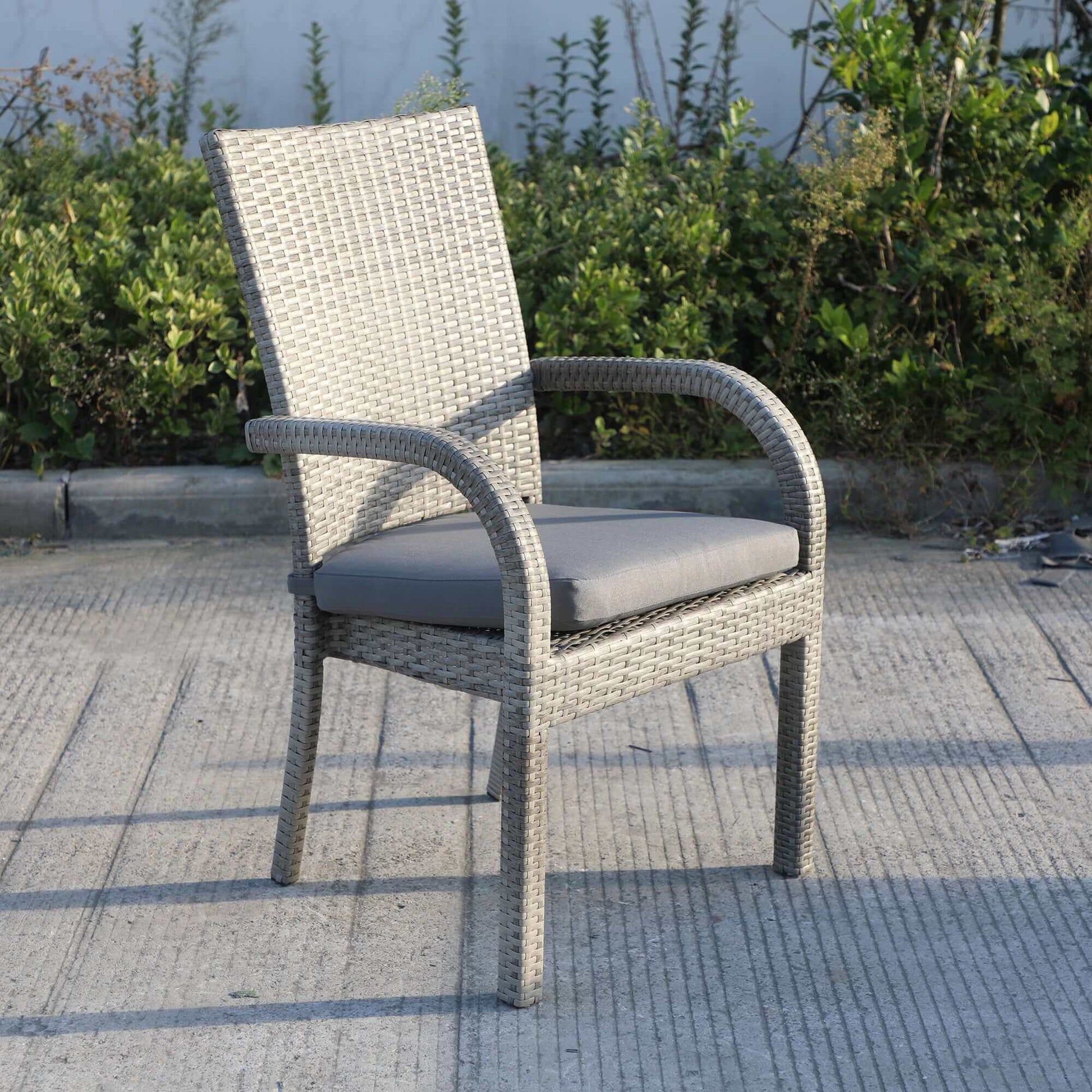 Gray wicker outdoor chair with cushion from the Balcones 9-Piece Outdoor Dining Table Set in a garden setting.